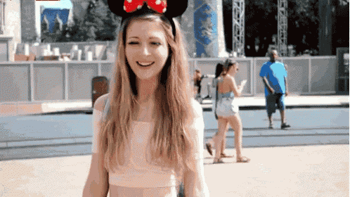 a woman wearing a pair of minnie mouse ears smiles at the camera