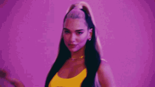 a close up of a woman wearing a yellow top and a necklace .