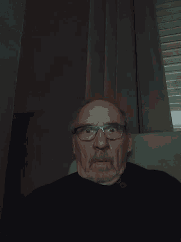 a man with glasses and a beard is looking down