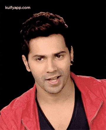 a close up of a man wearing a red jacket and black shirt .