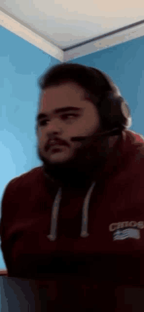 a blurry picture of a man wearing headphones and a red sweatshirt that says crew on it