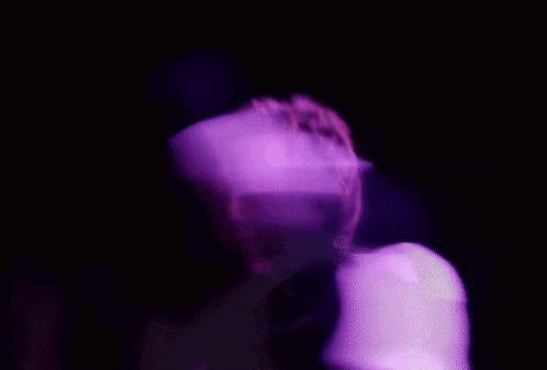 a man and a woman are dancing in a dark room with purple lights behind them .