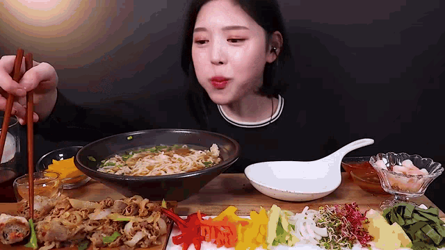 a woman is eating a bowl of soup with chopsticks .