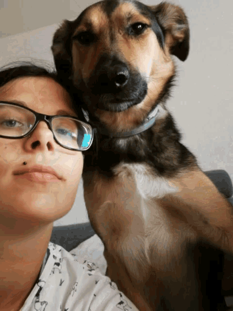 a woman with glasses holds a brown and black dog