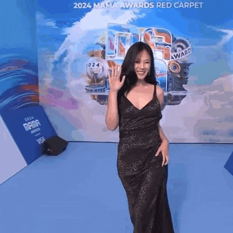 a woman in a black dress is standing on a red carpet at the 2024 mama awards .