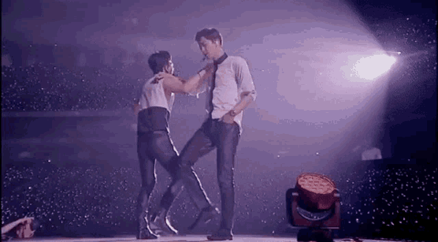 a couple of men are dancing on a stage .