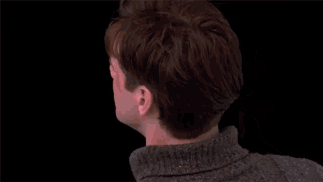 a close up of a man wearing a sweater with his eyes closed .