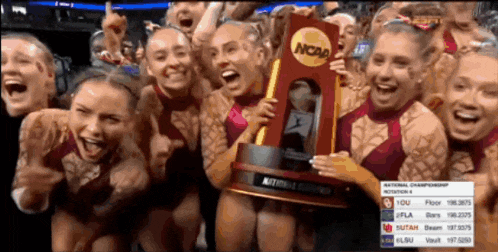 a group of cheerleaders holding up a trophy that says ncaa