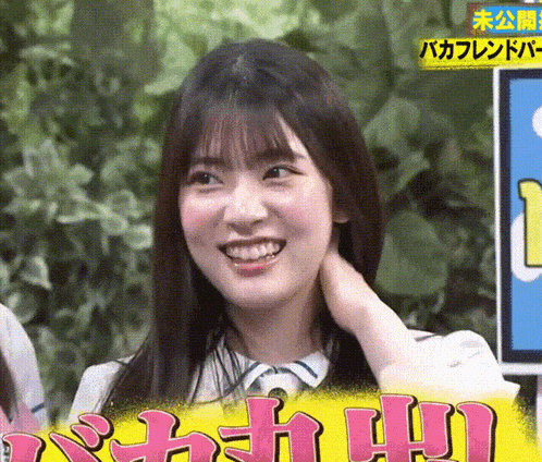a girl is smiling and holding her neck in front of a sign that says ' i '