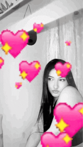 a woman is sitting in front of a window with pink hearts surrounding her .