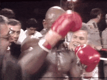 a man wearing red boxing gloves holds another man 's arm