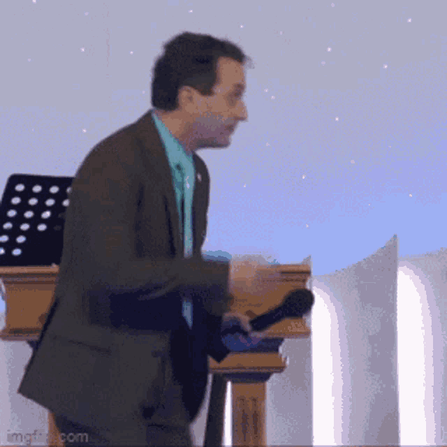 a man in a suit is holding a microphone in front of a podium