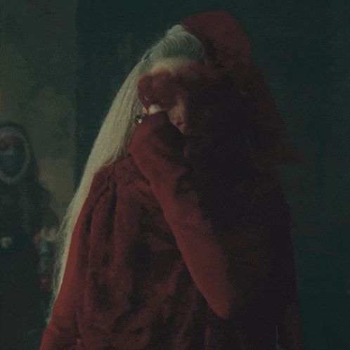 a woman with a ring on her finger covering her face with a red cloth