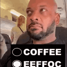a man with a beard is sitting on an airplane holding a sign that says `` coffee efffoc '' .