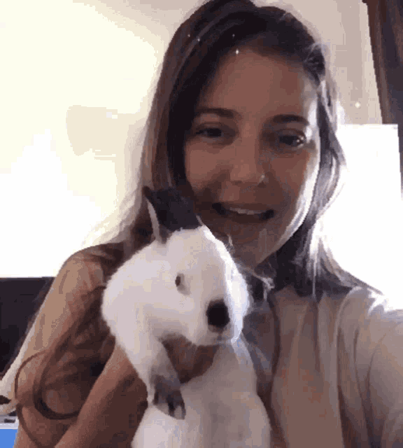 a woman is holding a white rabbit and smiling
