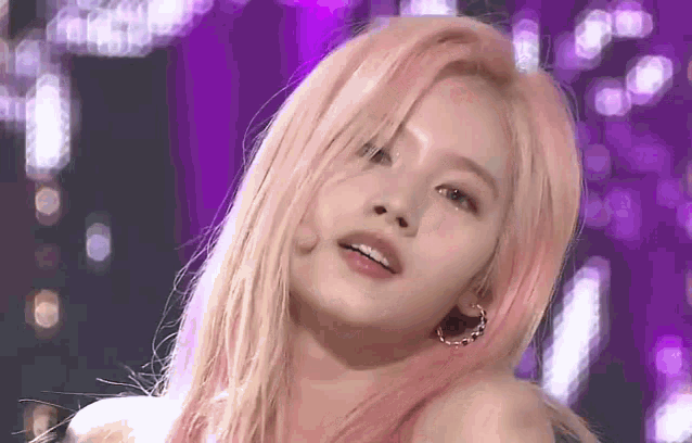 a close up of a woman 's face with pink hair on a purple background .