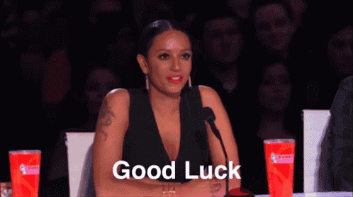 a woman is sitting in front of a microphone with the words `` good luck '' written on the screen behind her .