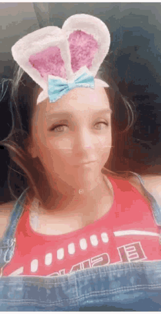 a woman wearing bunny ears and overalls looks at the camera .