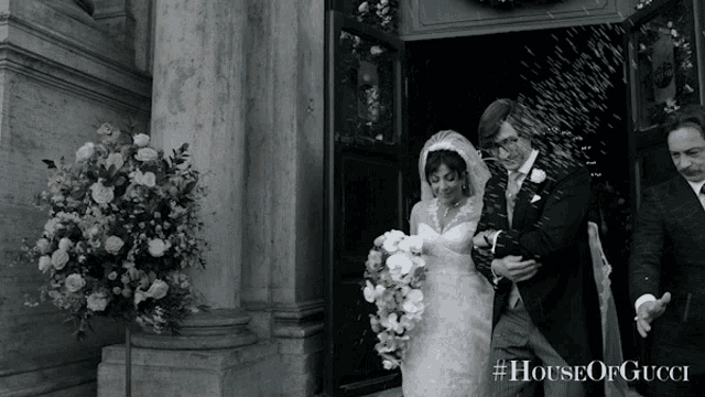 a bride and groom are walking out of a church with #houseofgucci written on the bottom right