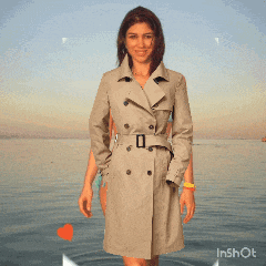 a woman in a trench coat is standing in the water