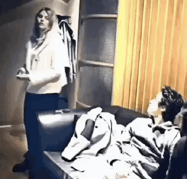 a woman is standing next to a person sitting on a couch .