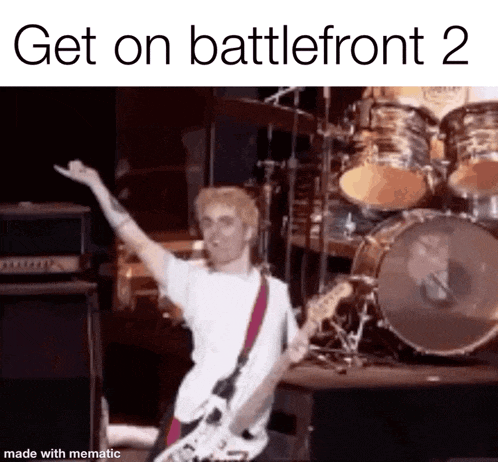 a man is playing a guitar on a stage with a drum set in the background .