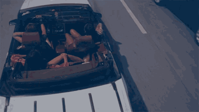 a group of people are sitting in the back of a convertible car
