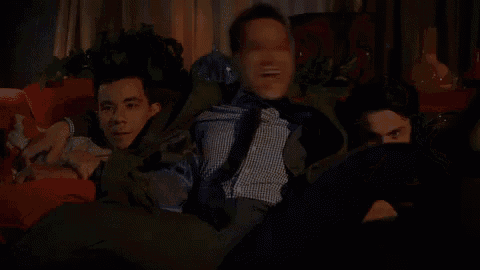 three men are sitting on a couch watching tv .