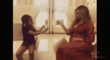 a woman in a red dress is dancing with a little girl in a living room .