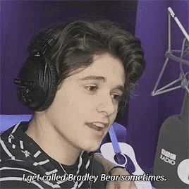 a young man wearing headphones is talking into a microphone and saying `` i get called bradley bear sometimes '' .