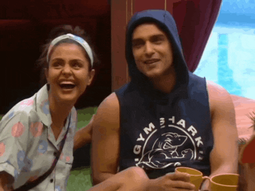 a man wearing a gymshark tank top laughs with a woman