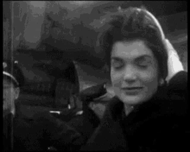 a black and white photo of a woman in a black coat