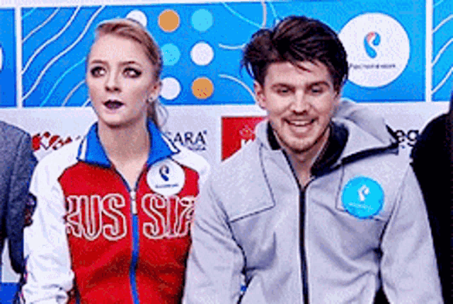 a man and a woman are standing next to each other in front of a sign that says russia