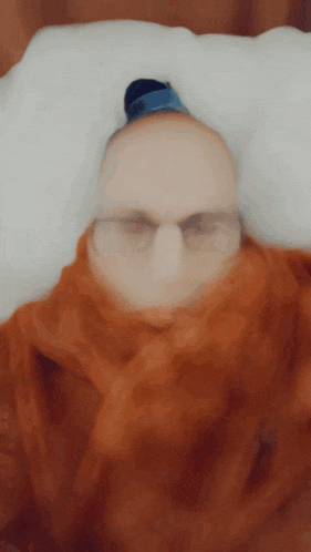 a blurry picture of a person with glasses and a scarf around their head