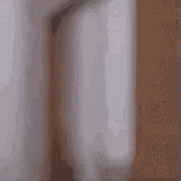a blurry picture of a man peeking out from behind a wooden door .
