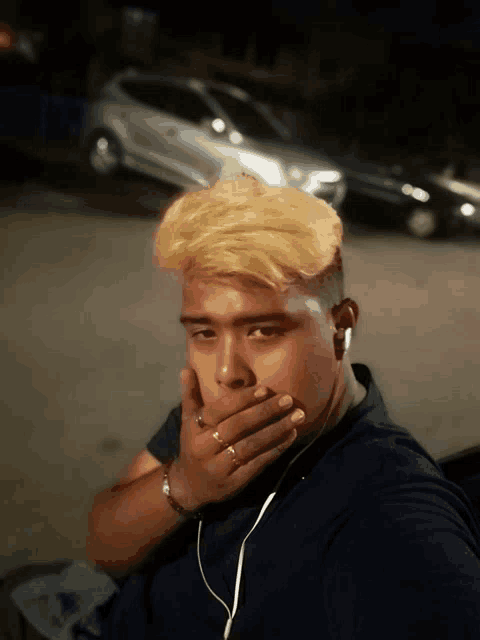 a man covering his mouth with his hand while wearing headphones