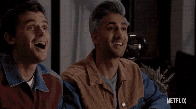 two men are laughing in front of a screen that says netflix on it