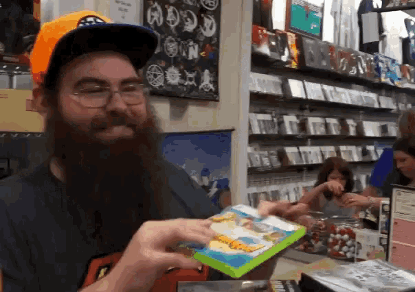 a man with a beard and glasses is holding a box with a picture of a cartoon character on it