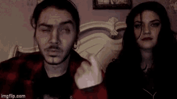a man and a woman are standing next to each other and the man is giving the middle finger .