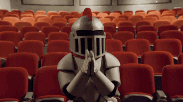 a man in a knight costume is praying in an empty auditorium