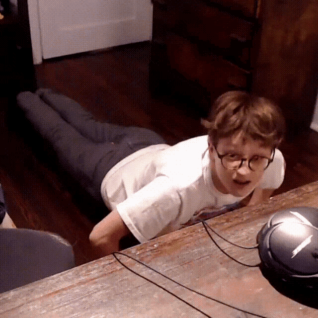 a man wearing glasses is laying on the floor