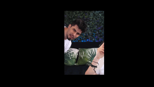 a man in a white shirt is laying on a couch with a palm tree pillow