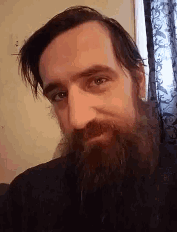 a man with a beard looks at the camera