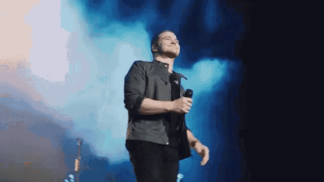 a man is singing into a microphone while standing on a stage