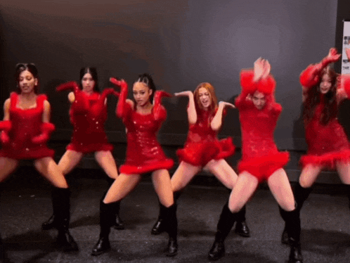 a group of women in red dresses and gloves are dancing on a stage