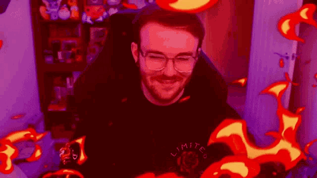 a man with glasses and a beard is sitting in a chair with flames coming out of it .