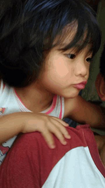 a little girl with blue hair is sitting on someone 's lap