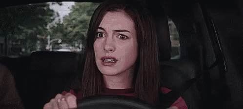 a woman is driving a car and making a surprised face .