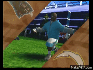 a man in a blue shirt is running on a field with a makeagif.com logo in the background