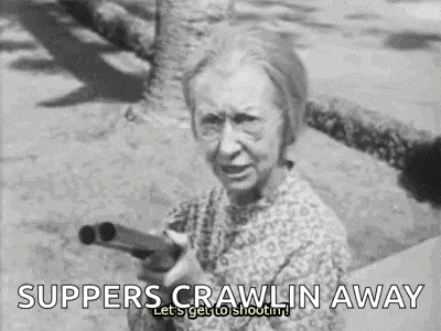 a black and white photo of an elderly woman holding a shotgun and saying supper crawlin away .
